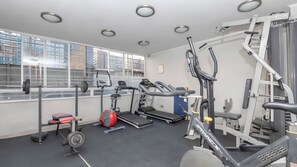 A gym with various exercise equipment including treadmills, a weight bench, and a squat rack. - Torre San Isidro by Domus Travels (Santiago)