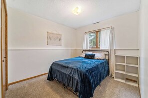 A bedroom with a single bed, a window with curtains, a wall-mounted shelf, and a light fixture. - 4BR 2BA, sleeps 8 Near ISU (Ames)
