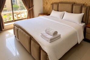 Quarto de hotel com uma cama grande, mesa de cabeceira, janela com cortinas e vista para o exterior.