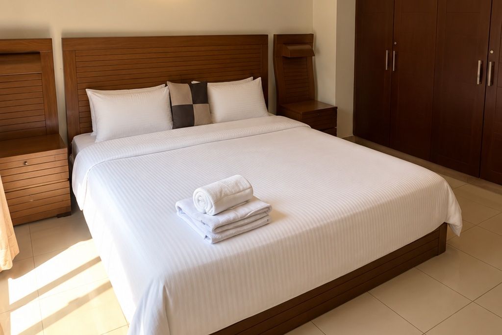 A hotel room with a large bed, wooden headboard, and a wardrobe.