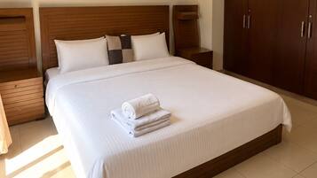 A hotel room with a large bed, wooden headboard, and a wardrobe.