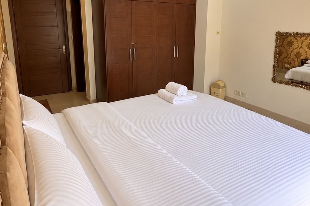 A hotel room with a large bed, a wardrobe, and a mirror on the wall.