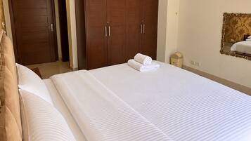 A hotel room with a large bed, a wardrobe, and a mirror on the wall.