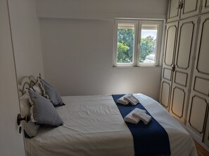 A bedroom with a bed, pillows, a window, and a wardrobe.