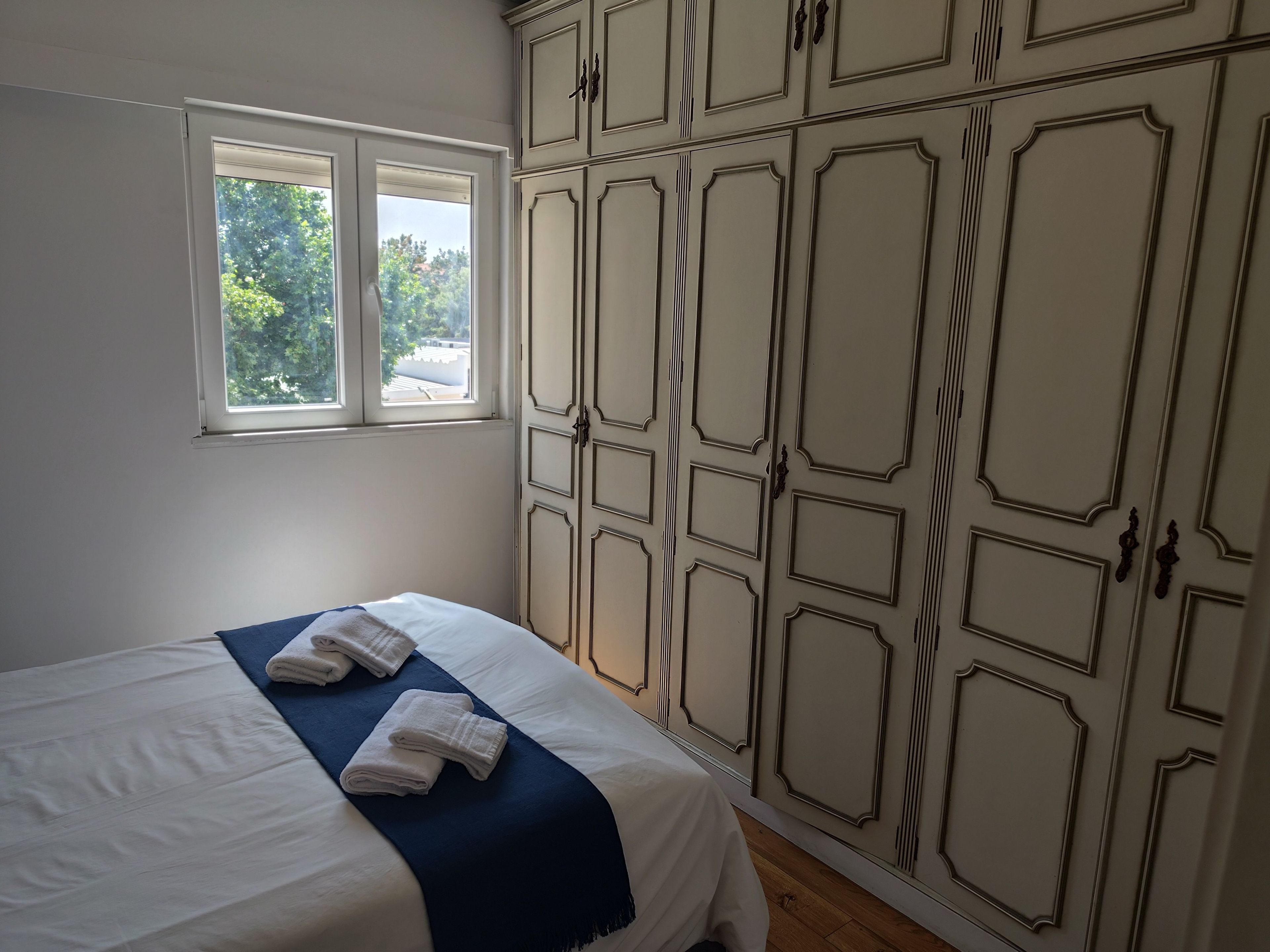Un dormitorio con una cama, una ventana y un armario con estampado geométrico.