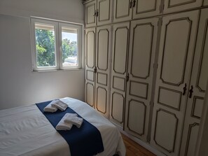 Un dormitorio con una cama, una ventana y un armario con estampado geométrico.
