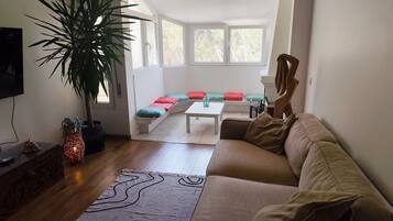 Una sala de estar con un sofá, una mesa de centro, una planta y un televisor.