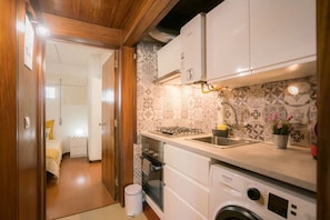 A compact kitchen with a gas stove, sink, and a washing machine.