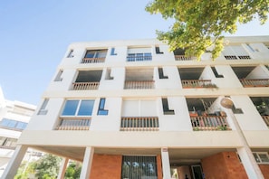 A multi-story residential building with balconies, large windows, and a flat roof.