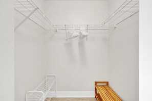 A room with a metal shelving unit, a wooden bench, and a white wall. - Golfer’s Paradise: Turnkey Rental with 24/7 Fitness & Premier Amenities (Naples)