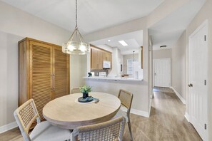 A dining area with a round table, chairs, and a hanging light fixture. - Golfer’s Paradise: Turnkey Rental with 24/7 Fitness & Premier Amenities (Naples)