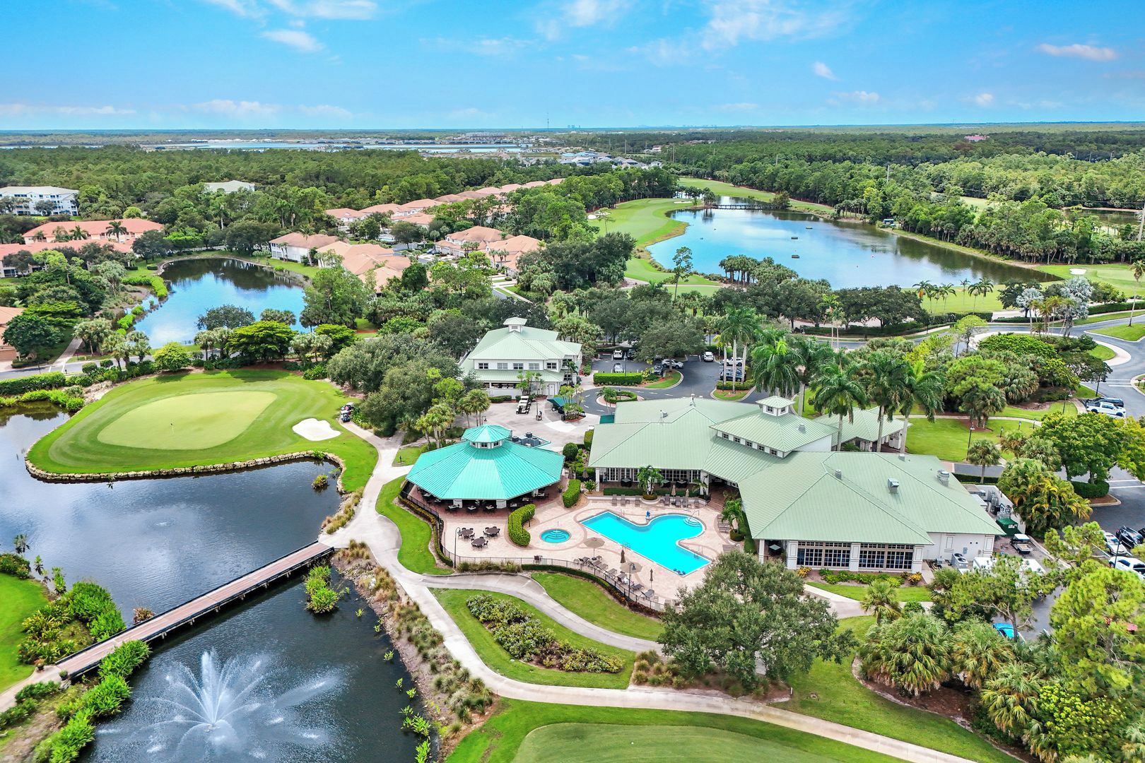 A golf course with a swimming pool, a bridge, and a large building with a green roof.
