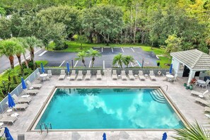 A rectangular pool with a surrounding deck, lounge chairs, and umbrellas. - Golfer’s Paradise: Turnkey Rental with 24/7 Fitness & Premier Amenities (Naples)