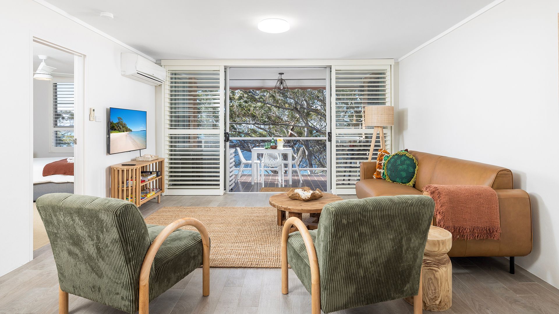 A modern living room with a sofa, two armchairs, a coffee table, and a television.