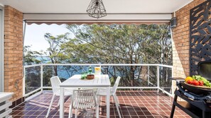 Un balcon avec une table, des chaises, un barbecue et une vue sur la mer.