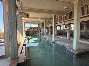 Área de piscina com deck de madeira, espreguiçadeiras e parede de pedra.