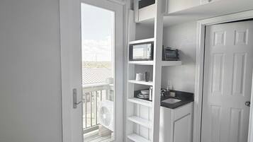 A compact bathroom with a white door, a built-in sink, and a small window.