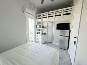 Une chambre avec un lit, une kitchenette équipée d’un réfrigérateur et un téléviseur.