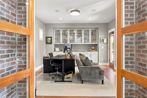 A modern home office with a desk, office chair, and a grey sofa.