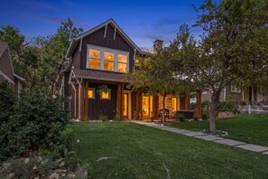 A two-story house with a front porch, a stone chimney, and a well-maintained lawn. - Boulder Luxury | Stunning 6BR on Boulder Foothills (Boulder)