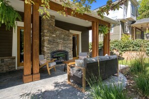 An outdoor patio with a stone fireplace, wooden furniture, and a stone wall. - Boulder Luxury | Stunning 6BR on Boulder Foothills (Boulder)