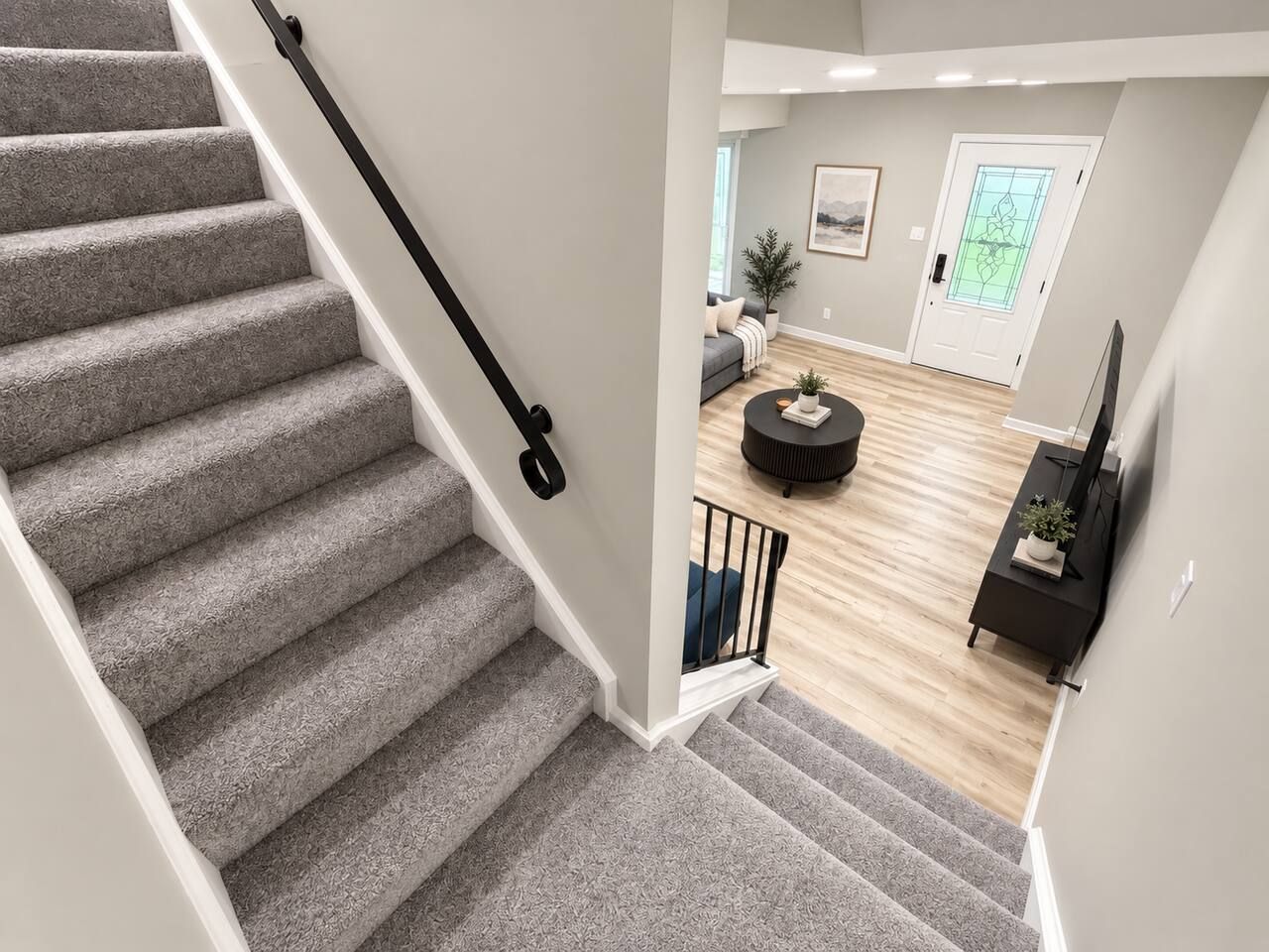 Eine Treppe führt zu einem Wohnbereich mit einer Couch, einem Couchtisch und einem Fernseher.