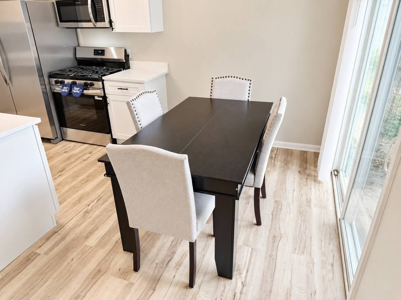 A modern kitchen with a dining table, chairs, and a built-in microwave.