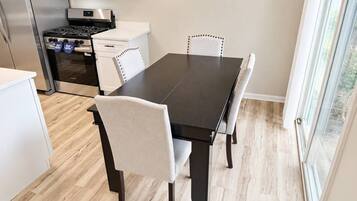 A modern kitchen with a dining table, chairs, and a built-in microwave.