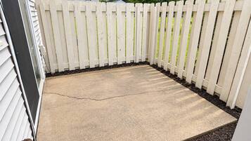 A concrete patio area enclosed by a white picket fence, with a visible crack in the concrete.