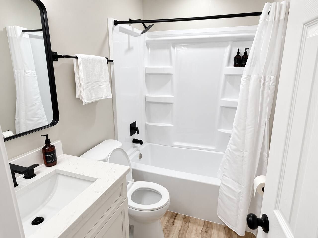 Ein modernes Badezimmer mit Waschbecken, Toilette und Badewanne, alles in Weiß.