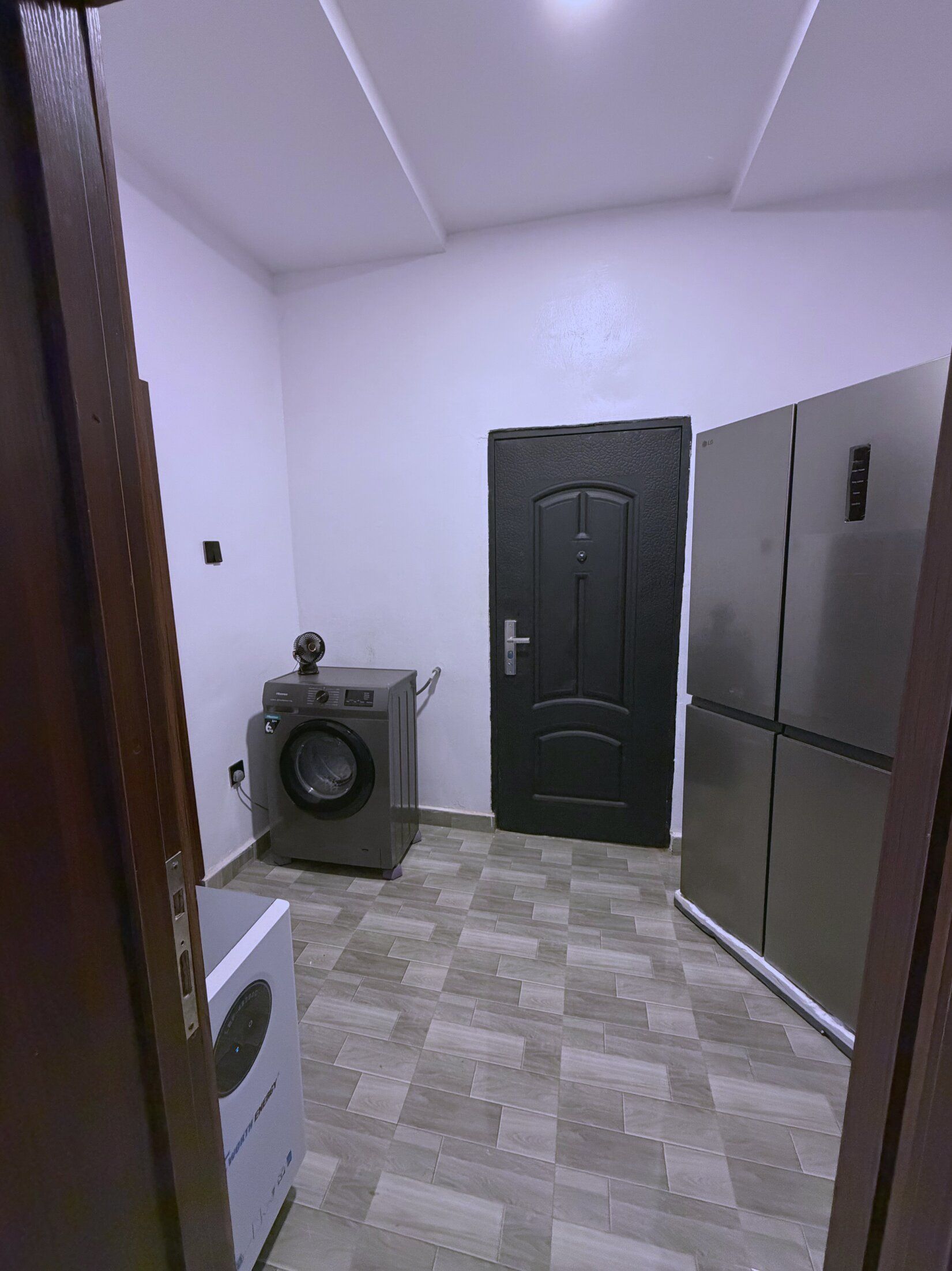 Une buanderie équipée d’un lave-linge, d’un sèche-linge et d’une porte noire.