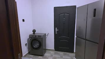 Une buanderie équipée d’un lave-linge, d’un sèche-linge et d’une porte noire.