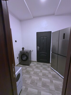 Ein Waschraum mit einer Waschmaschine, einem Trockner und einer schwarzen Tür.