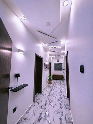 A hallway with a marble floor, recessed lighting, a wall-mounted clock, and a small plant. - Lyton CriB (Abeokuta)