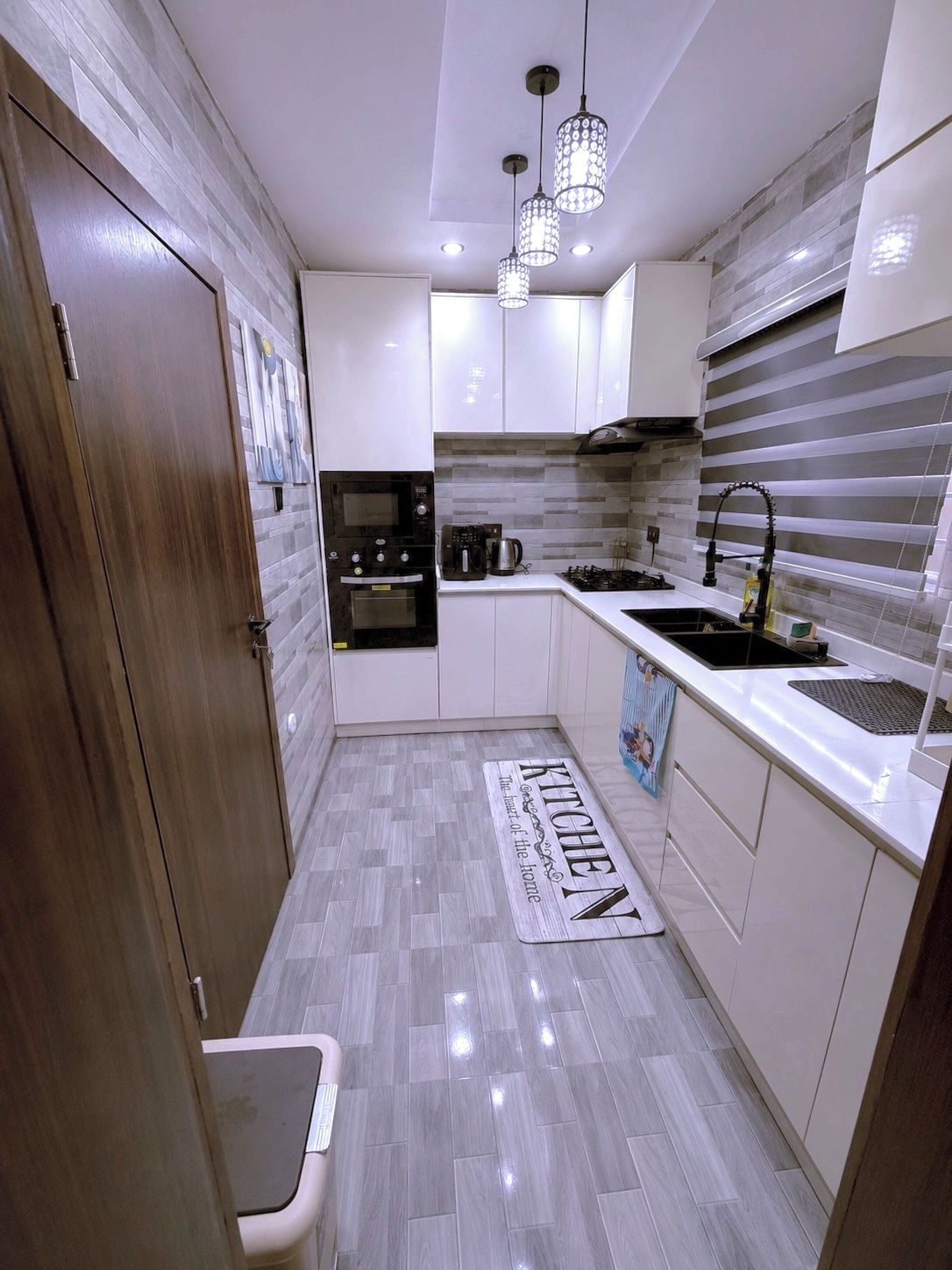 A modern kitchen with white cabinets, a stainless steel sink, a gas stove, and a built-in oven.