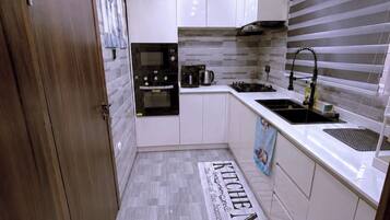 A modern kitchen with white cabinets, a stainless steel sink, a gas stove, and a built-in oven.