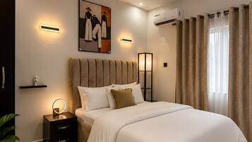 A modern bedroom with a large bed, bedside tables, a wall-mounted air conditioner, and a painting.