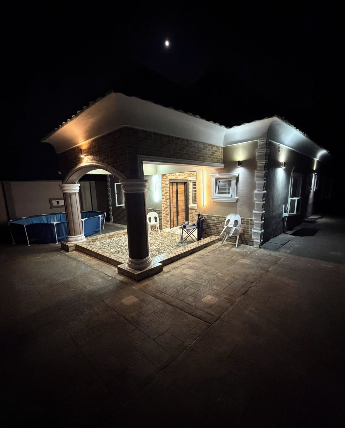 Uma casa com varanda coberta, piscina e fachada de tijolos.