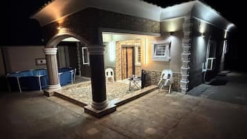Uma casa com varanda coberta, piscina e fachada de tijolos.