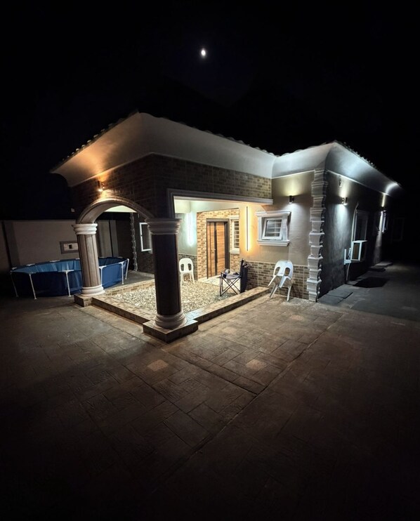 A house with a covered patio area, a pool, and a brick exterior.