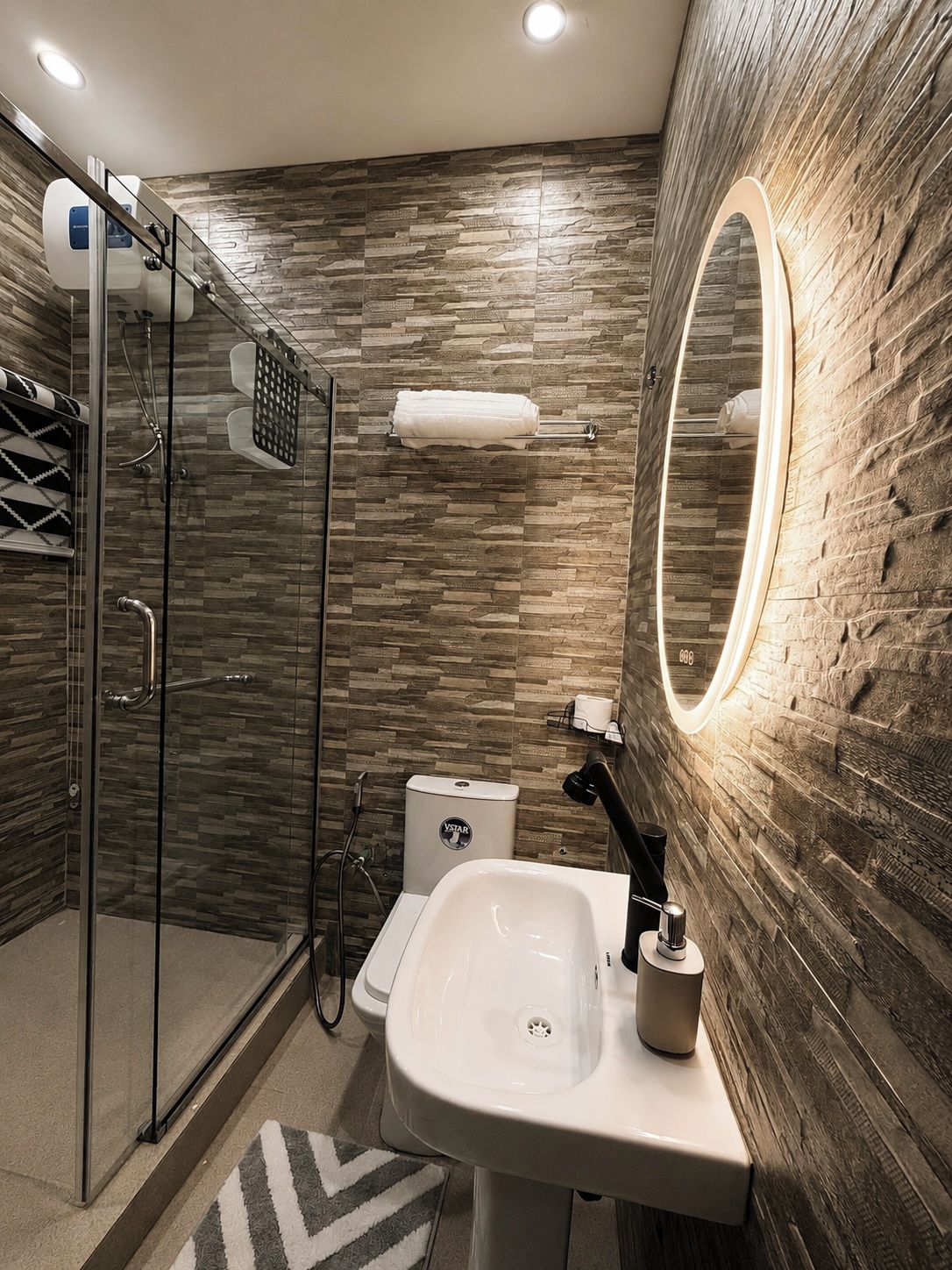 A modern bathroom with a glass shower enclosure, a white sink, and a large mirror.