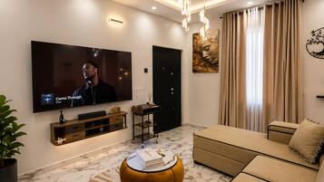A modern living room with a flat-screen TV, a sofa, a coffee table, and a patterned rug.