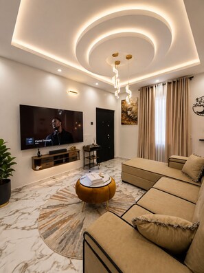 A modern living room with a flat-screen TV, a sofa, a coffee table, and a patterned rug. - Lyton CriB (Abeokuta)