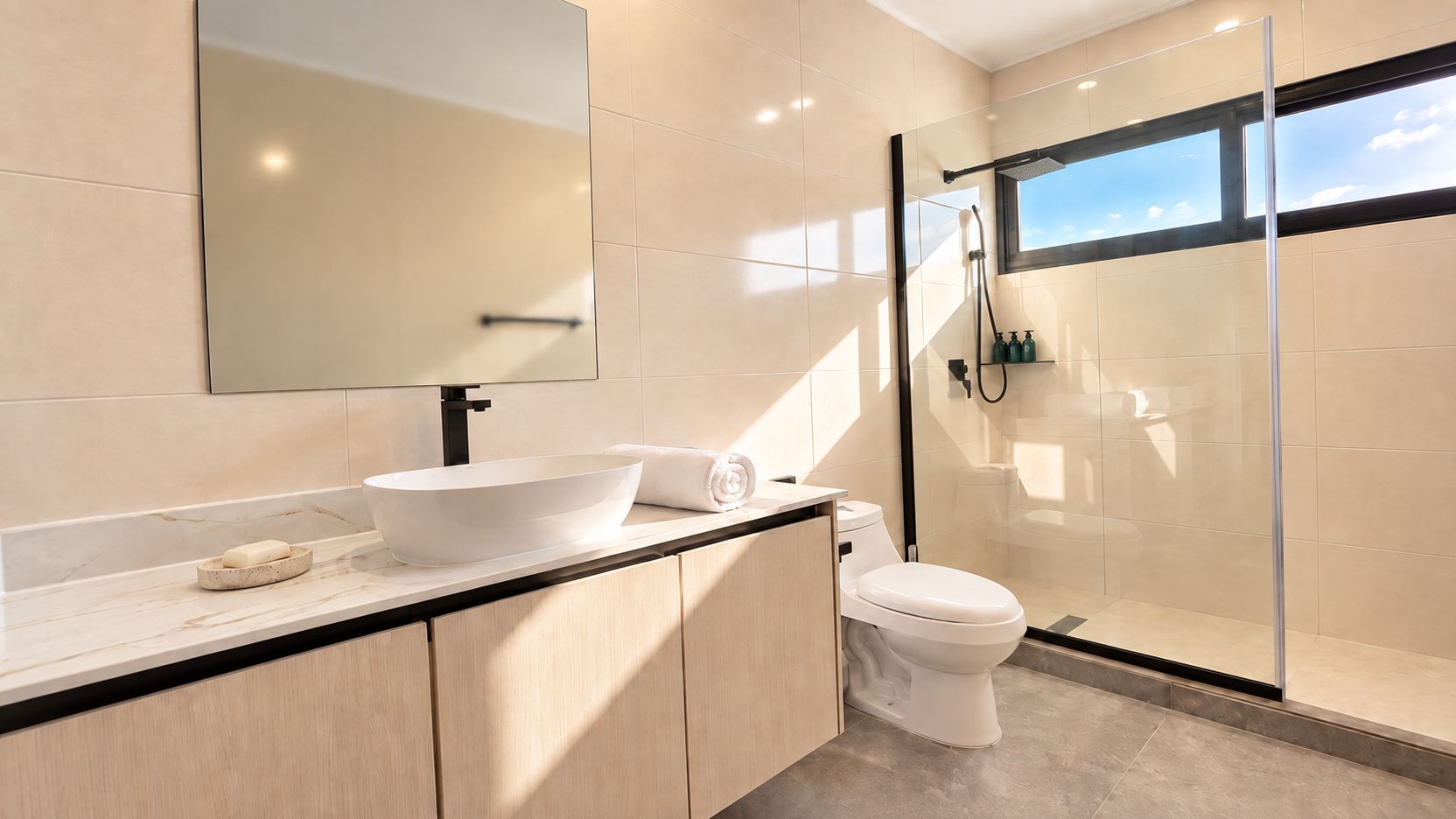 Een moderne badkamer met een groot wit wastafelmeubel, een toilet en een douchecabine met glazen wanden.