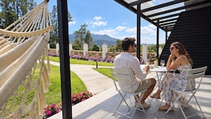 A couple dining at an outdoor table with a view of a garden and mountains. - Natura Lodge by Villa Alejandro (Bajo Boquete)