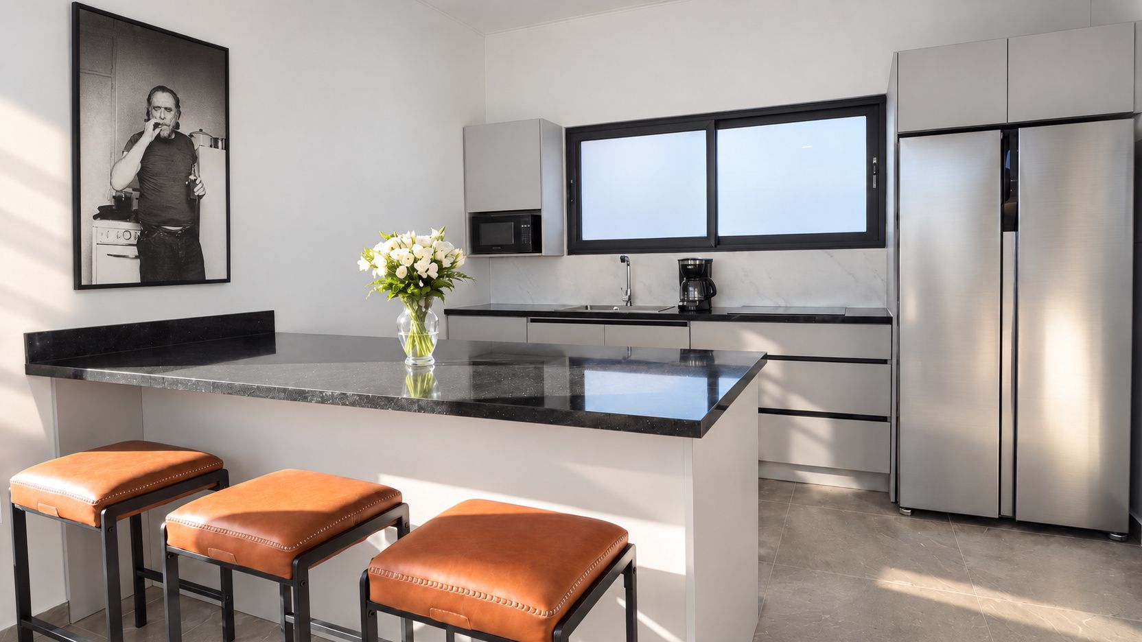 A modern kitchen with a central island, stainless steel appliances, and a large window.