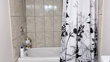 A bathroom with a bathtub, toilet, and shower area.