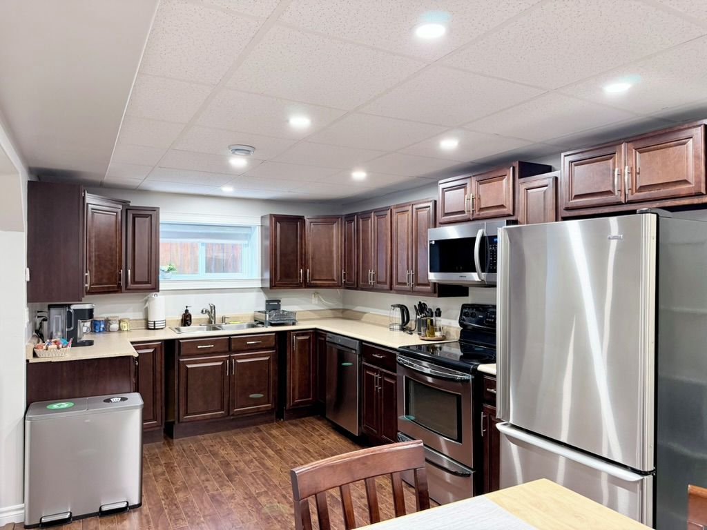 A modern kitchen with wooden cabinets, stainless steel appliances, and a window providing natural light.