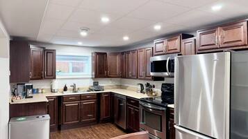 A modern kitchen with wooden cabinets, stainless steel appliances, and a window providing natural light.