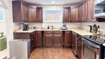 A kitchen with dark wooden cabinets, a stainless steel refrigerator, a dishwasher, and a stove.